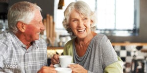 Mature Couple with Dental Implants Smiling and Holding Tea Cups